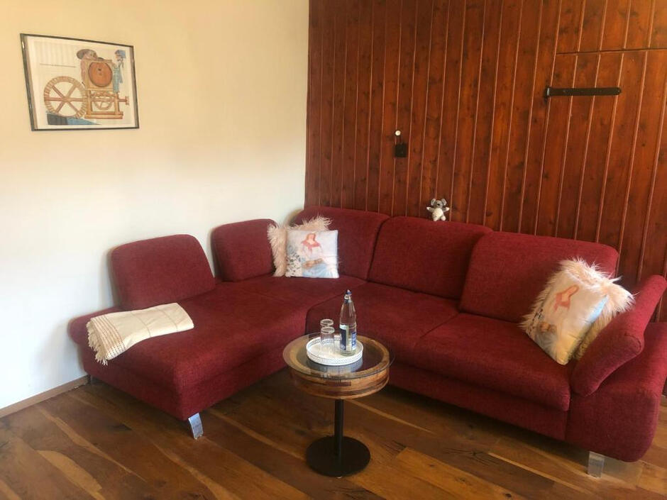 Gemütliches Wohnzimmer Wohnzimmer mit großer Eckcouch, Holzwand und stilvoller Einrichtung für entspannte Stunden in der Wassermühle Bruchmühlen.
