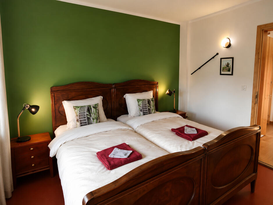 Gemütliches Gästezimmer Helles Doppelzimmer mit historischen Holzmöbeln, komfortablen Betten und gemütlicher Atmosphäre in der Wassermühle Bruchmühlen.